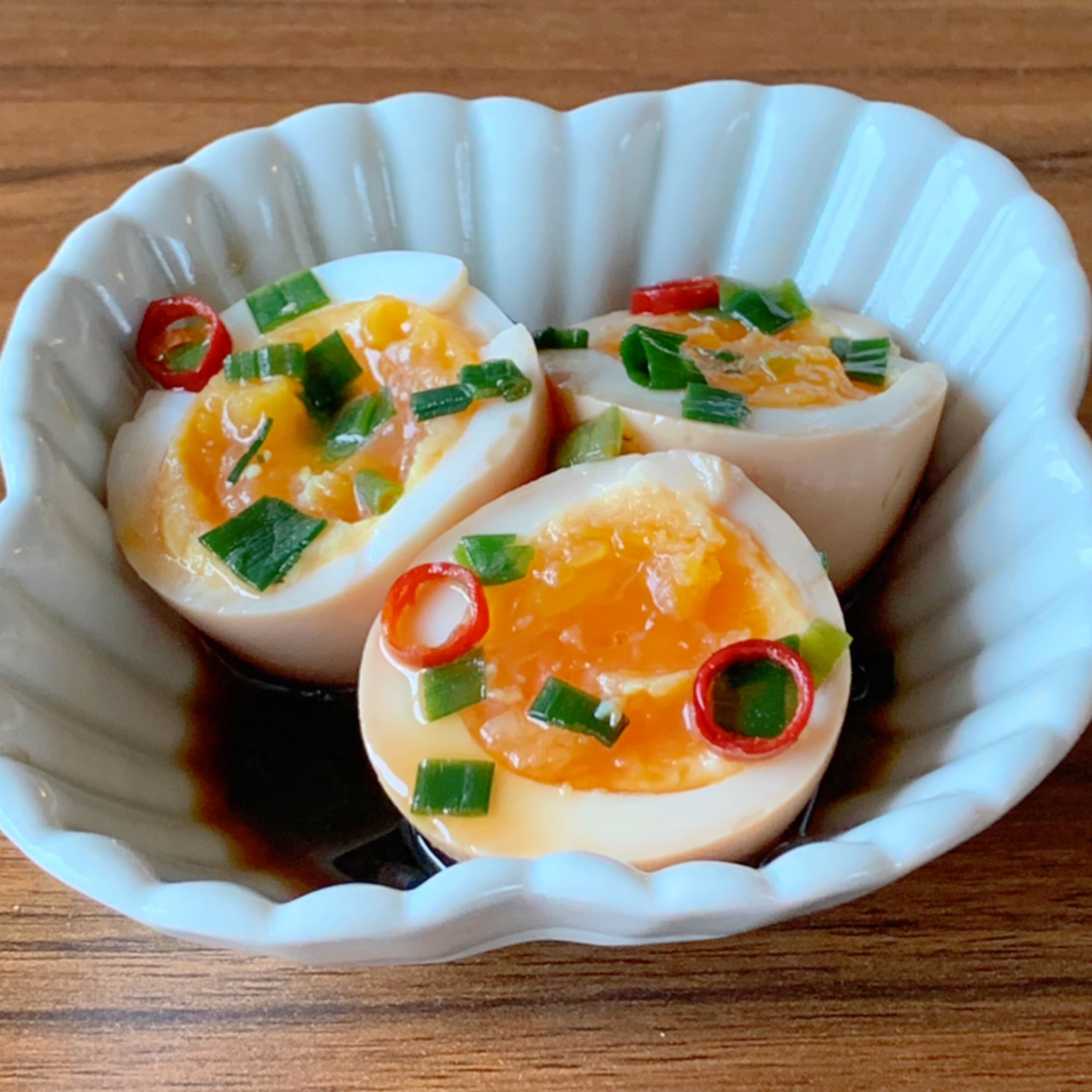 Boiled eggs are marinated in a sauce that combines soy sauce, mirin, sesame oil, and red pepper.