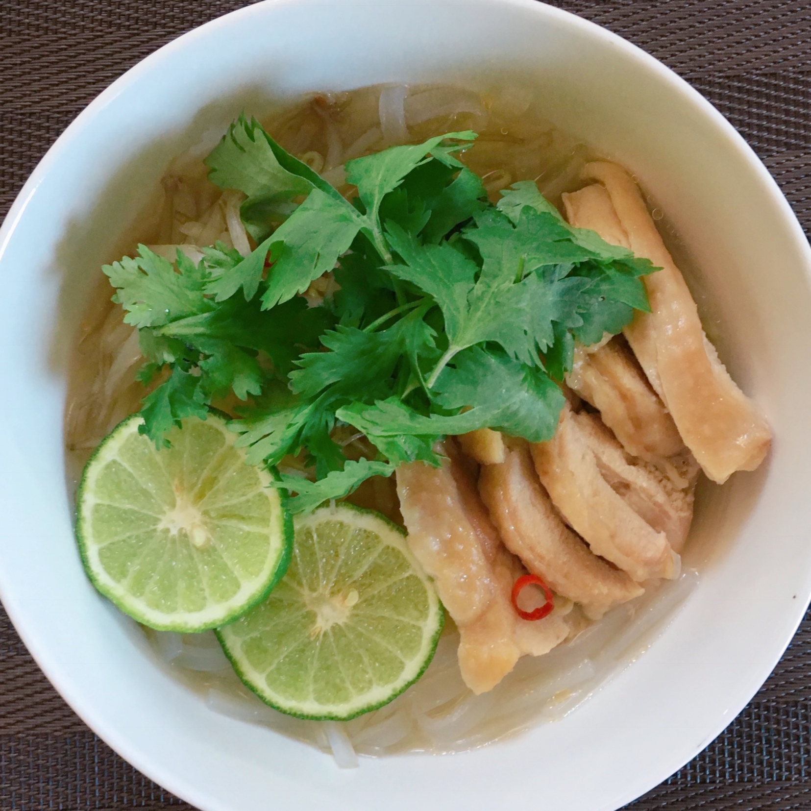 Noodles called pho are topped with soup seasoned with fish sauce, chicken, and coriander.