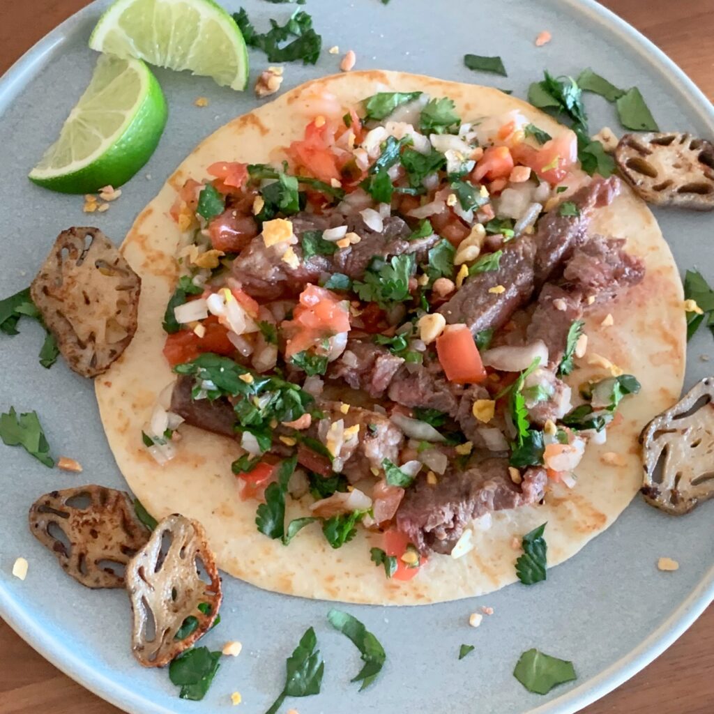 A taco made of beef topped with plenty of salsa made with tomatoes, coriander, and chili peppers.
