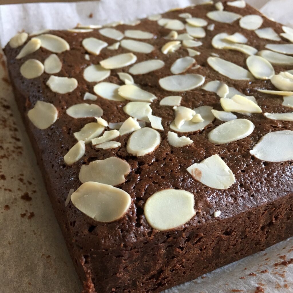 A brownie made with plenty of chocolate. It is topped with almond slices.