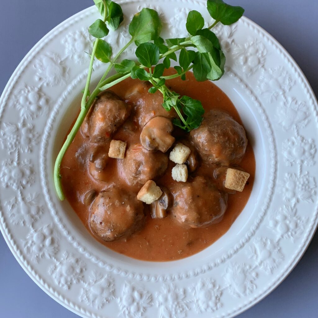 Meatballs are simmered in a sauce made from tomatoes, white sauce, and milk. 

The mild acidity of the tomatoes and the richness of the white sauce make this a very delicious dish.