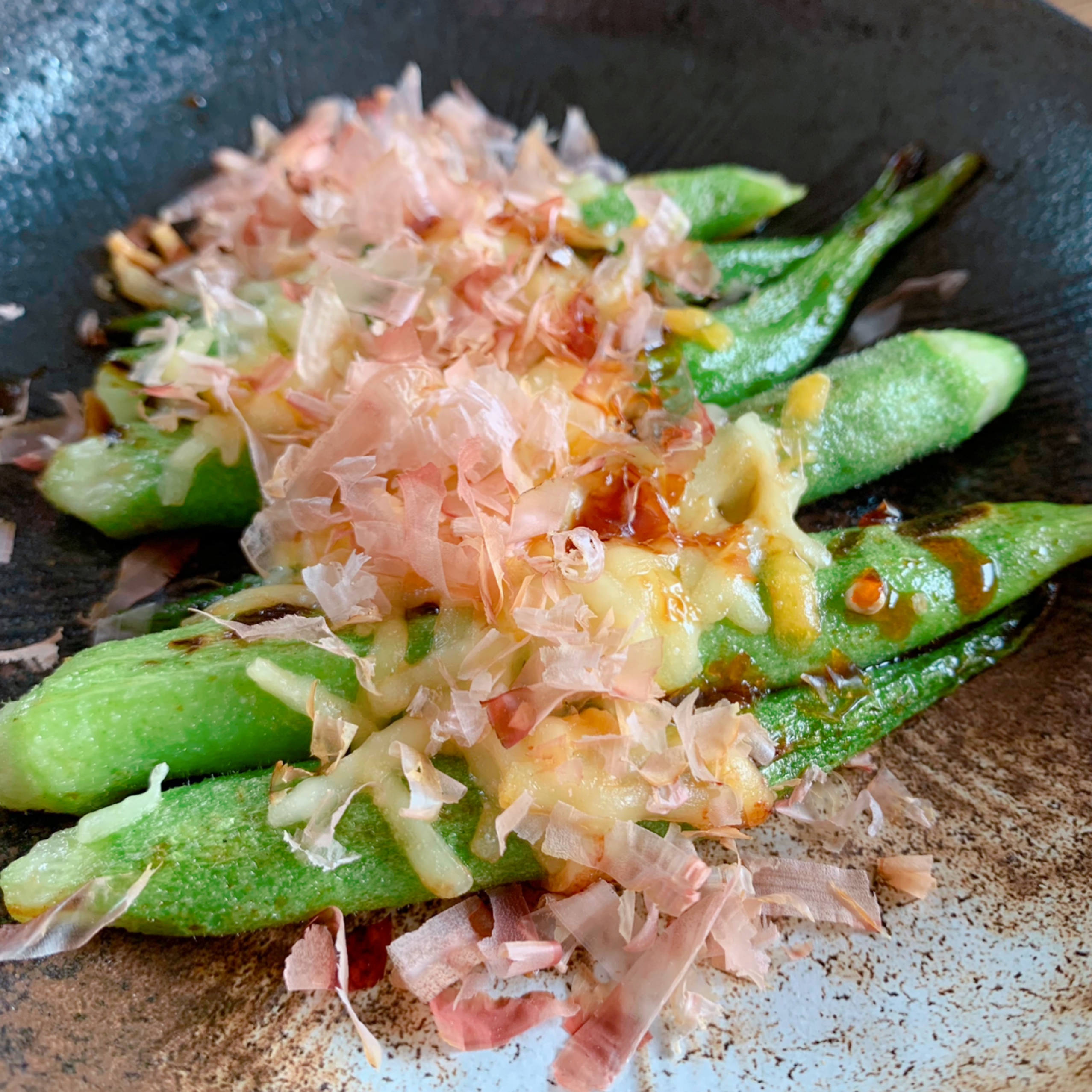 Okra, which is in season in the summer, is grilled and topped with cheese and bonito flakes